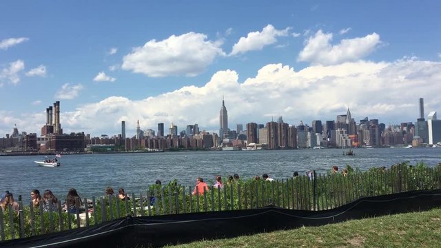 NEW YORK CITY - July 2015: Shot of Manhattan skyline from park in Williamsburg, Brooklyn.  Midtown and upper east side of Manhattan can be seen with Empire State Building and Chrysler Building.  Peopl