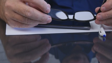 Businessman Hands Taking Eyeglasses from the Table to Read a Document