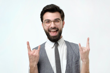 Happy attractive european adult showing rock signs with both hands and shouting out loud, expressing joy. Studio shoot.