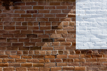 Old brick wall with white paint in one corner and triangular shadow