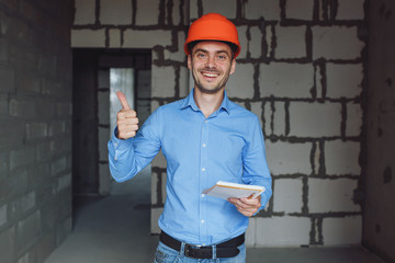 Construction supervisor writes on notebook near the wall. Handsome foreman taking notes in...