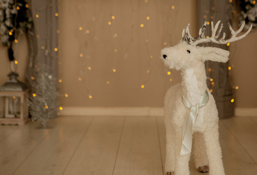 Christmas decoration, a white deer representation figurine on red garlands and Christmas lights background © volody10