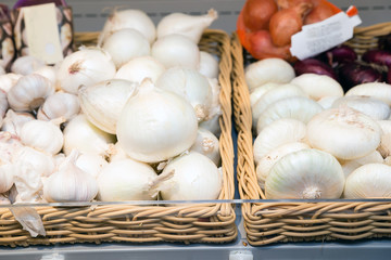 Fresh white onions in a square wicker basket in the window of a grocery store, supermarket