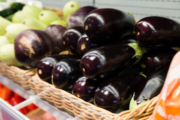 Fresh eggplant in a square wicker basket on the showcase of a grocery store, supermarket