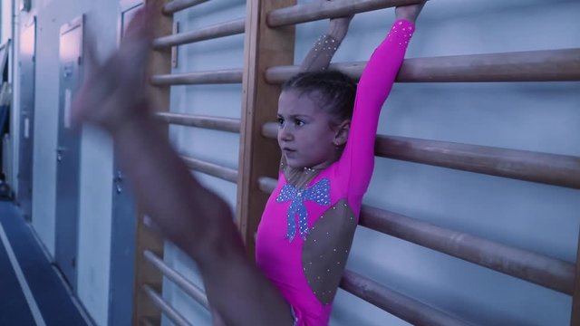 little girl doing sports raises her legs up. preparation for the competition.