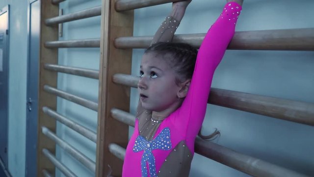 little girl doing sports raises her legs up. preparation for the competition.