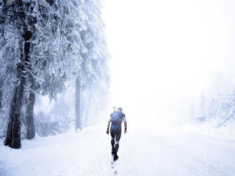 Man walking on a snow covered road in winter