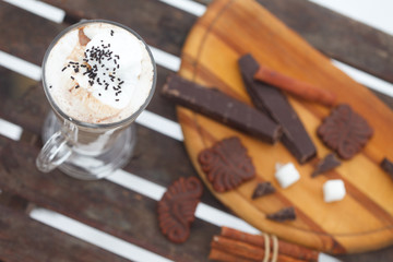 Glass of  Hot chocolate or cappuchino with whipped cream and cinnamon sticks, top view