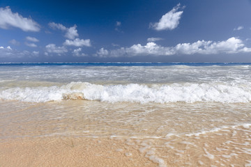 Fototapeta na wymiar Soft Wave Of Blue Ocean On Sandy Beach. Background. Splash of waves on the sandy beach. foam, surf, waves