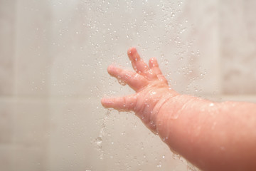 Fototapeta premium Hand Of Newborn Caucasian Baby Under Shower Close Up With Lots Of Splashes
