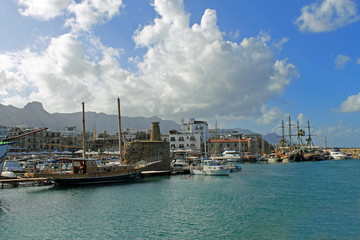 Fototapeta na wymiar Alte Hafenanlage von Kyrenia im Norden von Zypern, mit alten Segelschiffen unter Schönwetterwolken am blauen Himmel