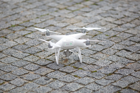 White flying quadrocopter with camera on green forest background