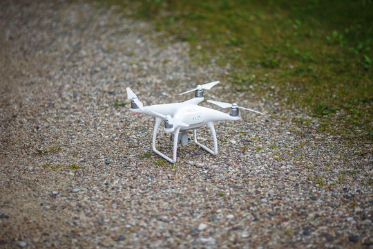 White flying quadrocopter with camera on green forest background