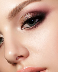 Closeup portrait of young beautiful woman with evening make up. Pink and gold multicolored smokey eyes. Luxury skincare and modern fashion makeup concept. Studio shot.
