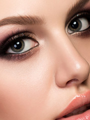 Fototapeta premium Closeup portrait of young beautiful woman with evening make up. Pink and gold multicolored smokey eyes. Luxury skincare and modern fashion makeup concept. Studio shot.