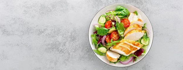 Foto op Plexiglas Eten Salade van gegrilde kipfilet, filet en verse groente van sla, rucola, spinazie, komkommer en tomaat. Gezonde lunchkaart. Diëet voeding. Bovenaanzicht. Banner