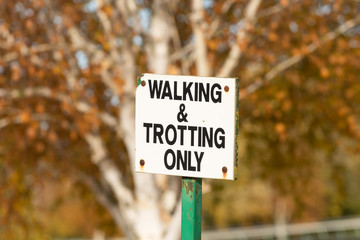 A sign stating walking and trotting only near racehorse training ground and stables.
