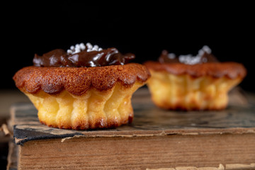 Tasty cupcakes decorated with chocolate and book loss. Dessert on a wooden table in the kitchen.