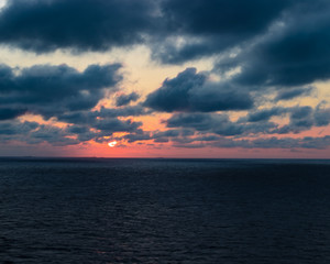 Naklejka na ściany i meble Beautiful Caribbean sunset with purple and red tones. Cloudy evening sky over the ocean in a tranquil warm scene.