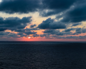 Obraz premium Beautiful Caribbean sunset with purple and red tones. Cloudy evening sky over the ocean in a tranquil warm scene.
