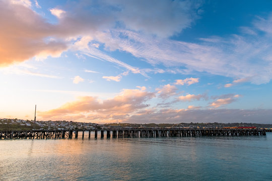 Beautiful sunset at the dock. Blue sky and Ocean with town view. Omaru, New Zealand.