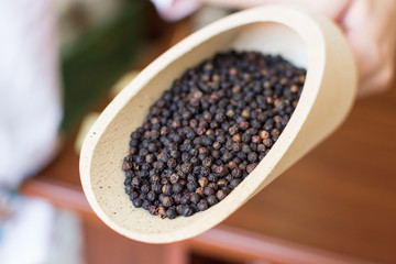 Black peppercorns closeup in wooden scoop
