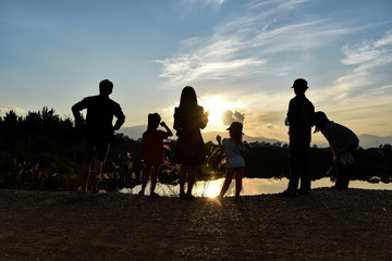 Fototapeta na wymiar Silhouette of a happy family at the dam while sunset with blue sky.