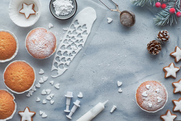 Top view of the table with sugar-sprinkled muffins, fondant icing and Christmas star cookies on light blue wood