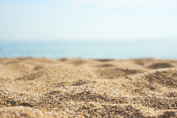 Sand on the beach close up with blurred sea and waves on a background.