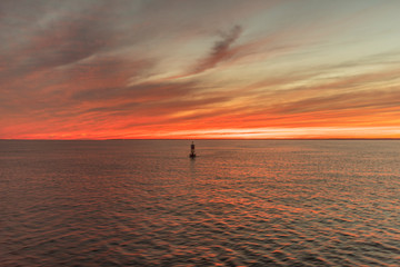 a buoy guards the entrace to a bay within a sunset in Cape Cod, Massachusetts