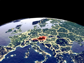 Austria from space on planet Earth at night with bright city lights. Detailed plastic planet surface with real mountains.