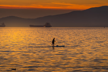 Naklejka na ściany i meble woman on paddlebard at sunset