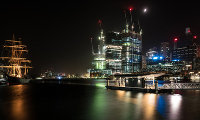Fototapeta na wymiar tall ship and city skyline at night
