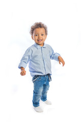 Little black kid with curly hair stand with arms spread to the side and smiling at camera, isolated background