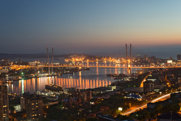 Fototapeta na wymiar The main city of Primorsky region Rossi city port of Vladivostok. The lights of Vladivostok night bridge over Golden Horn Bay