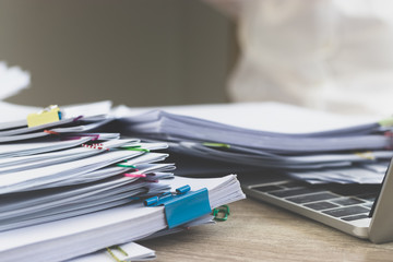 Pile of unfinished homework assignment and report separated by colorful paper clips on teacher's...