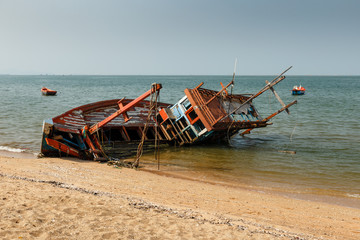 fishing boat crashed lies on its side near the shore, old shipwreck
