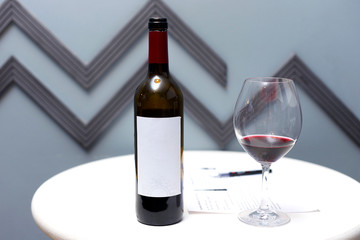 a bottle of red wine, a glass and a corkscrew