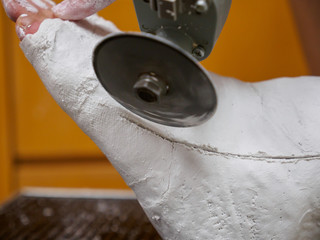 Closeup of a doctor removing a plaster cast of a healed leg fracture with an orthopedic safety saw near a patient's foot. Healthcare and medicine.