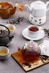 Tea card. Different in appearance teapots on a gray background, different types of tea. Tea still life.