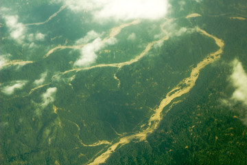 sandy river bed among hilly green woodland. aerial photography white clouds over the valley