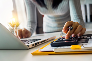 Businesswoman calculates financials with graph paper on the table on the cost of home office in the evening.