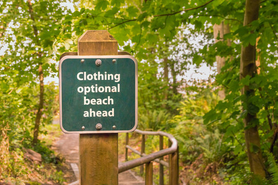 Clothing optional sign on post on trail to beach, British Columbia