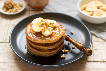 Pancakes with banana, nuts and honey, served with tea. Rustic style.