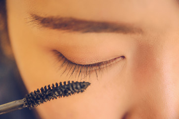Beauty face of woman by applying mascara on face and smooth skin by cosmetics.