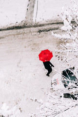 person with umbrella crossing the snowy street