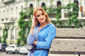 Fototapeta premium Young beautiful woman in dress on summer city street