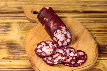 Sliced salami sausage on cutting board on wooden table