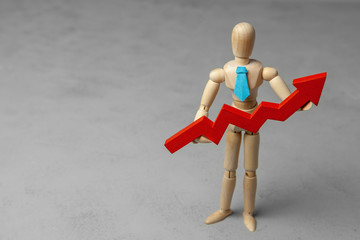 Wooden man in tie holds red arrow up. Copy space for text.