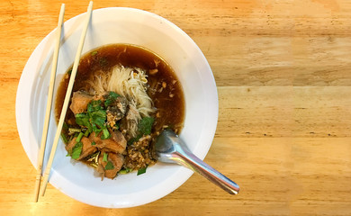 Dish of noodle with pork soup on Yellow wooden table for lunch time, Asian street food